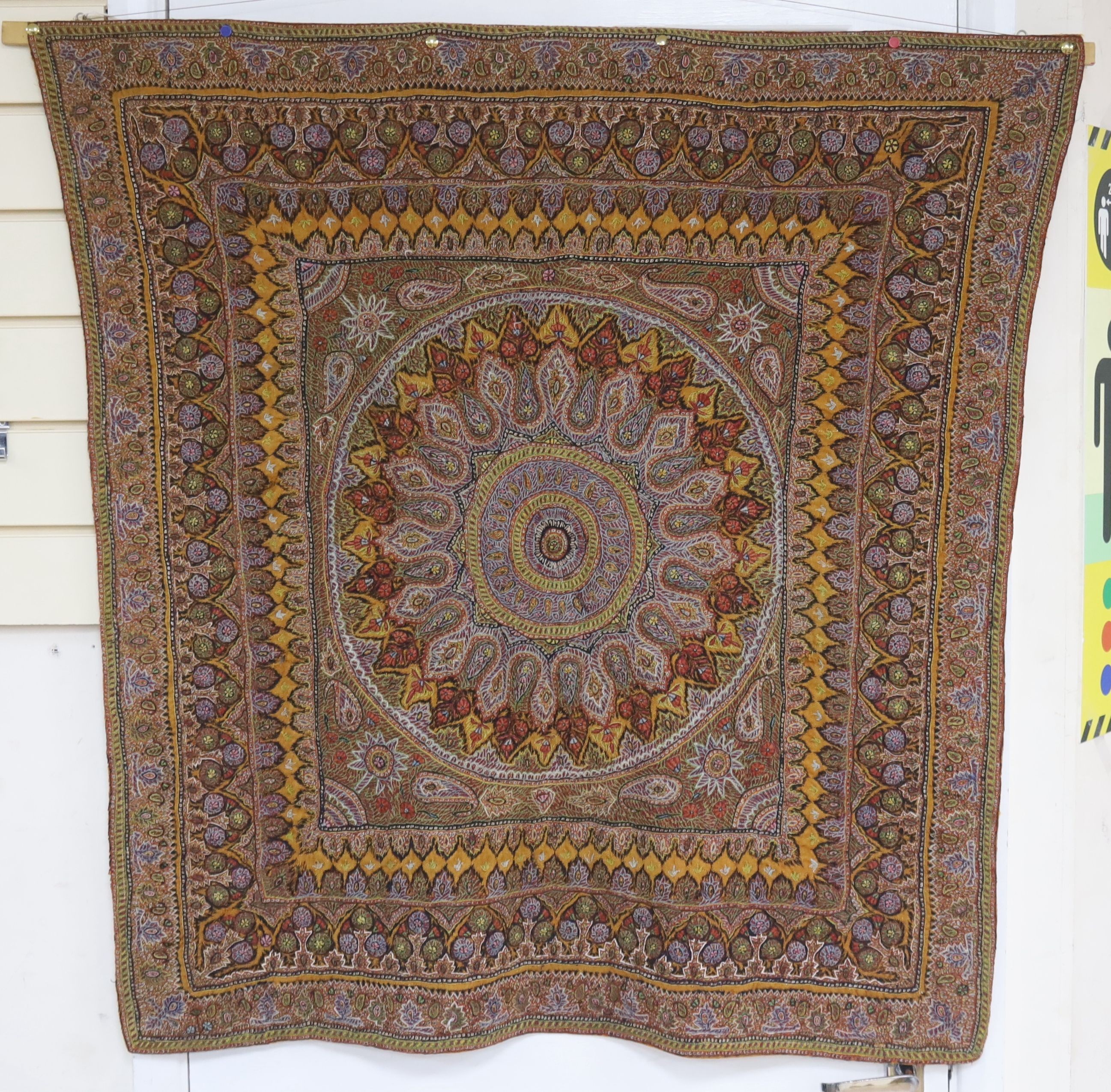 A Kashmiri wool embroidered hanging, with central cartouche, 97 cms wide x 99 cms high.